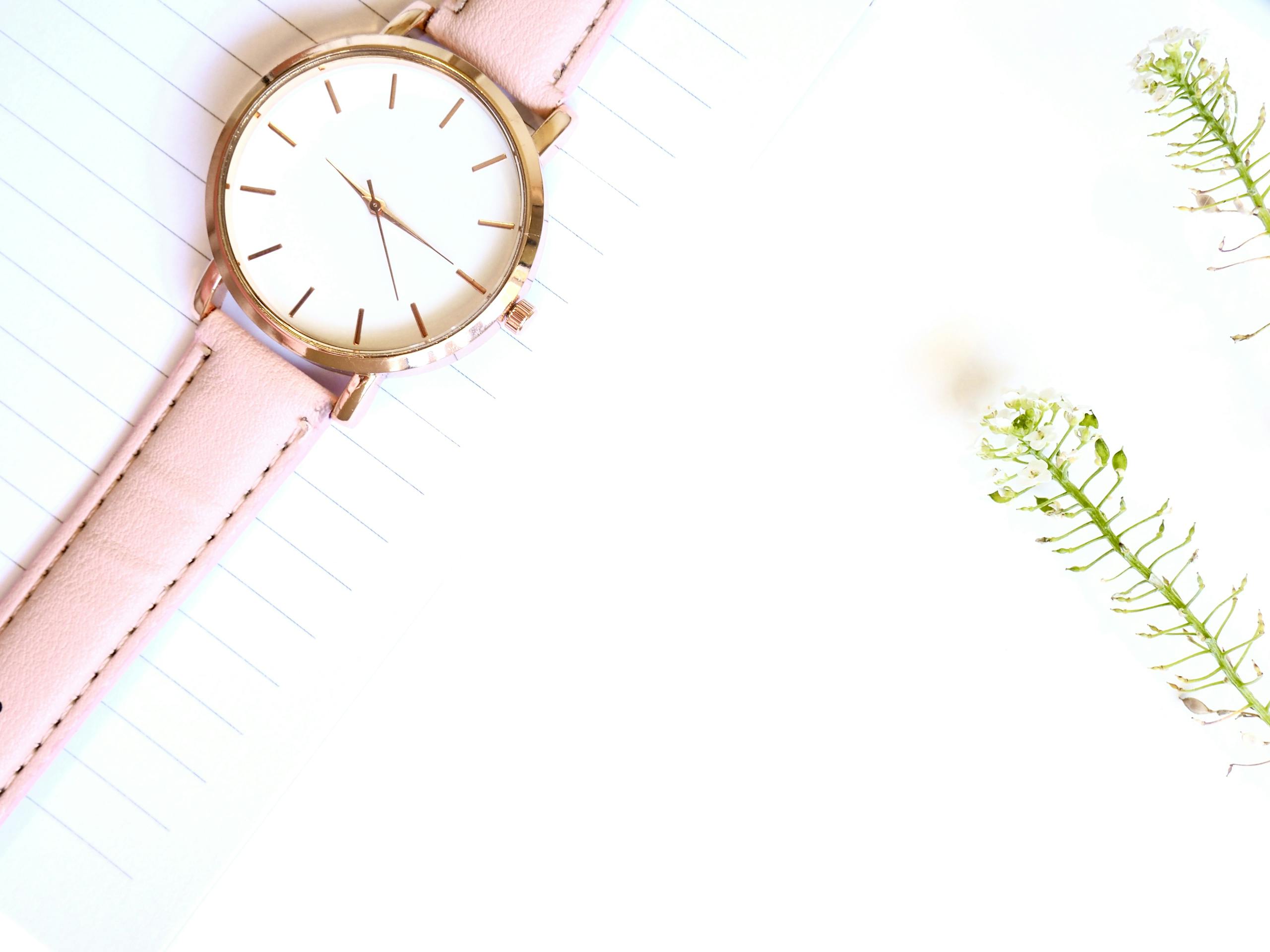 A stylish rose gold watch on paper with delicate flowers, perfect for minimalistic design concepts.