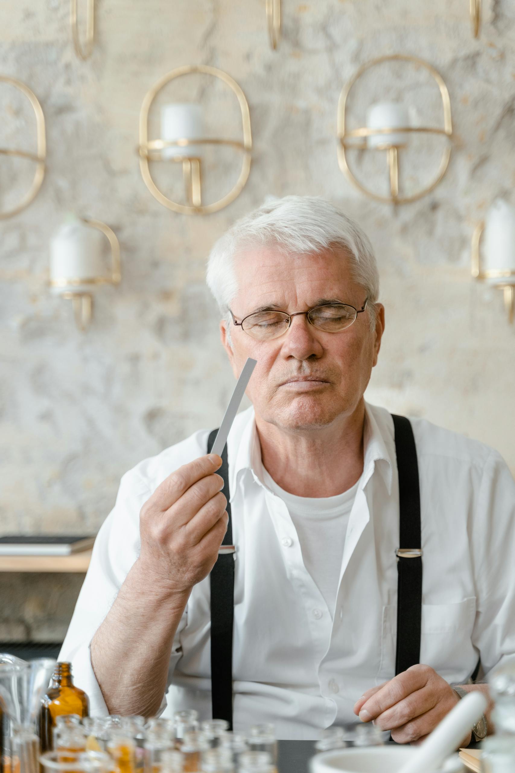Senior man in suspenders smelling fragrance strip in a cosmetic store.