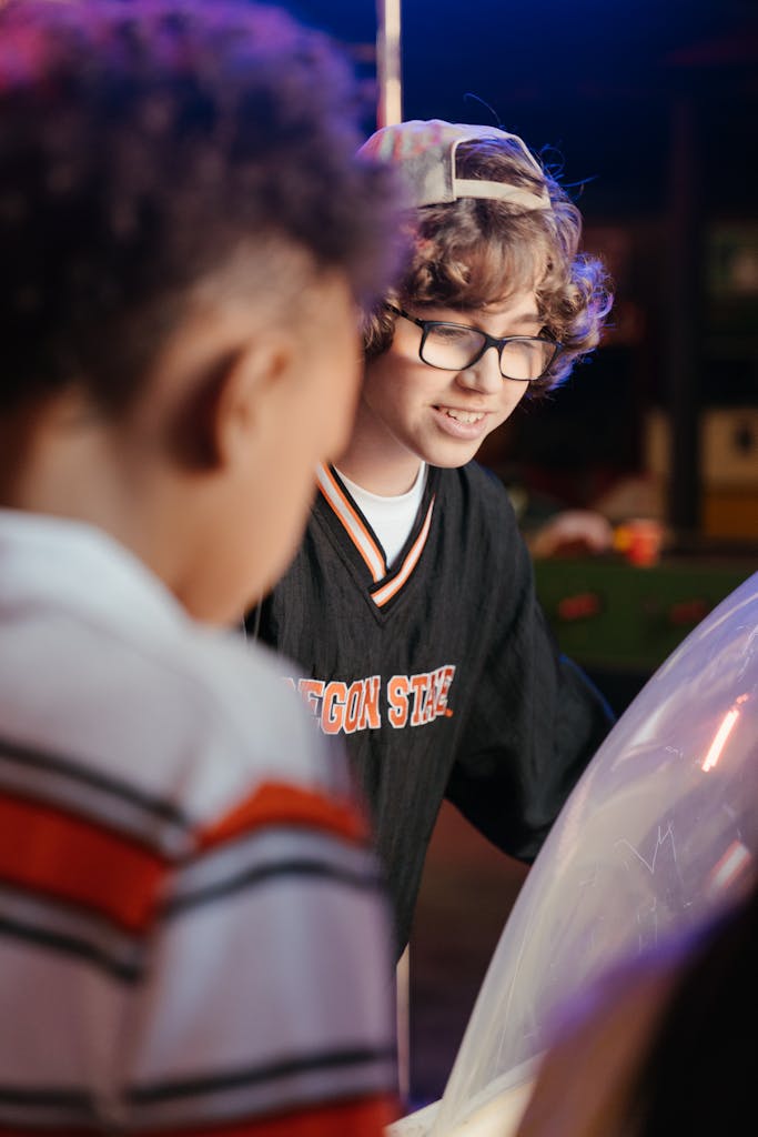 Teens play an exciting arcade game indoors, emphasizing youthfulness and camaraderie.