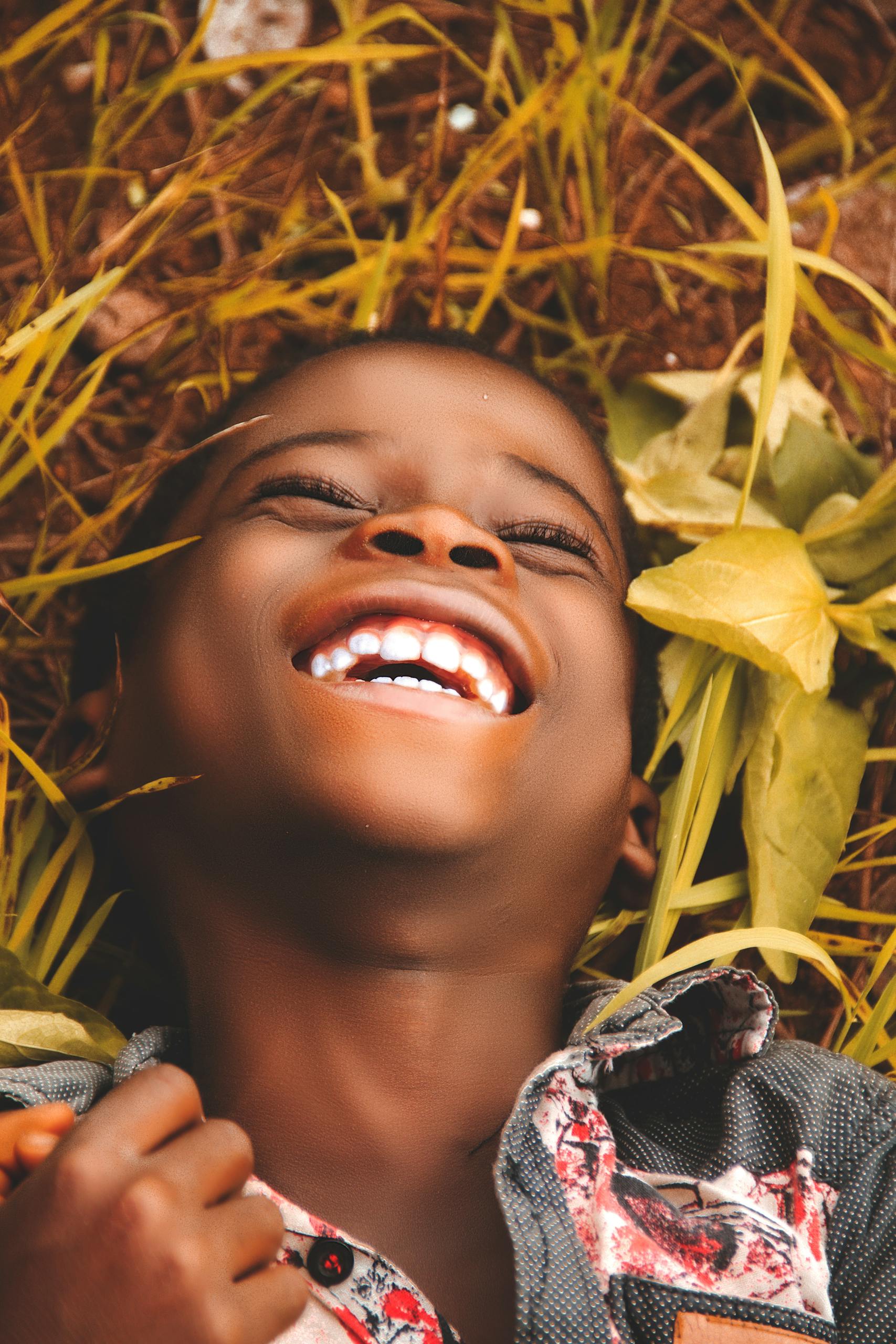 A happy African boy smiling while lying on grass in Enugu, Nigeria.