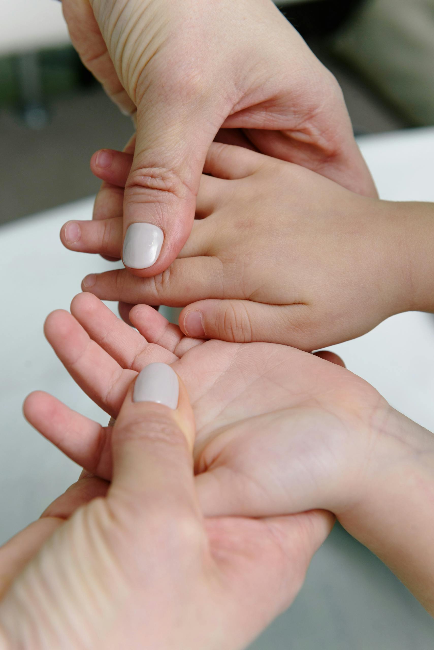 Adult giving a soothing hand massage to a child's hand, emphasizing care and relaxation.