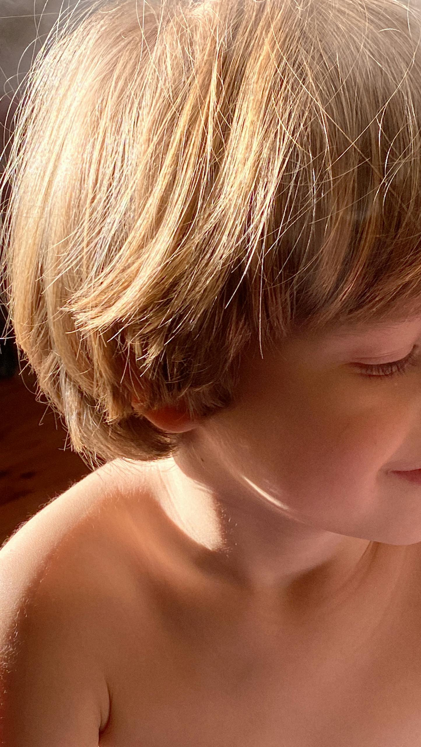 Charming sunlit portrait of a smiling child with blonde hair capturing the essence of innocence and joy.