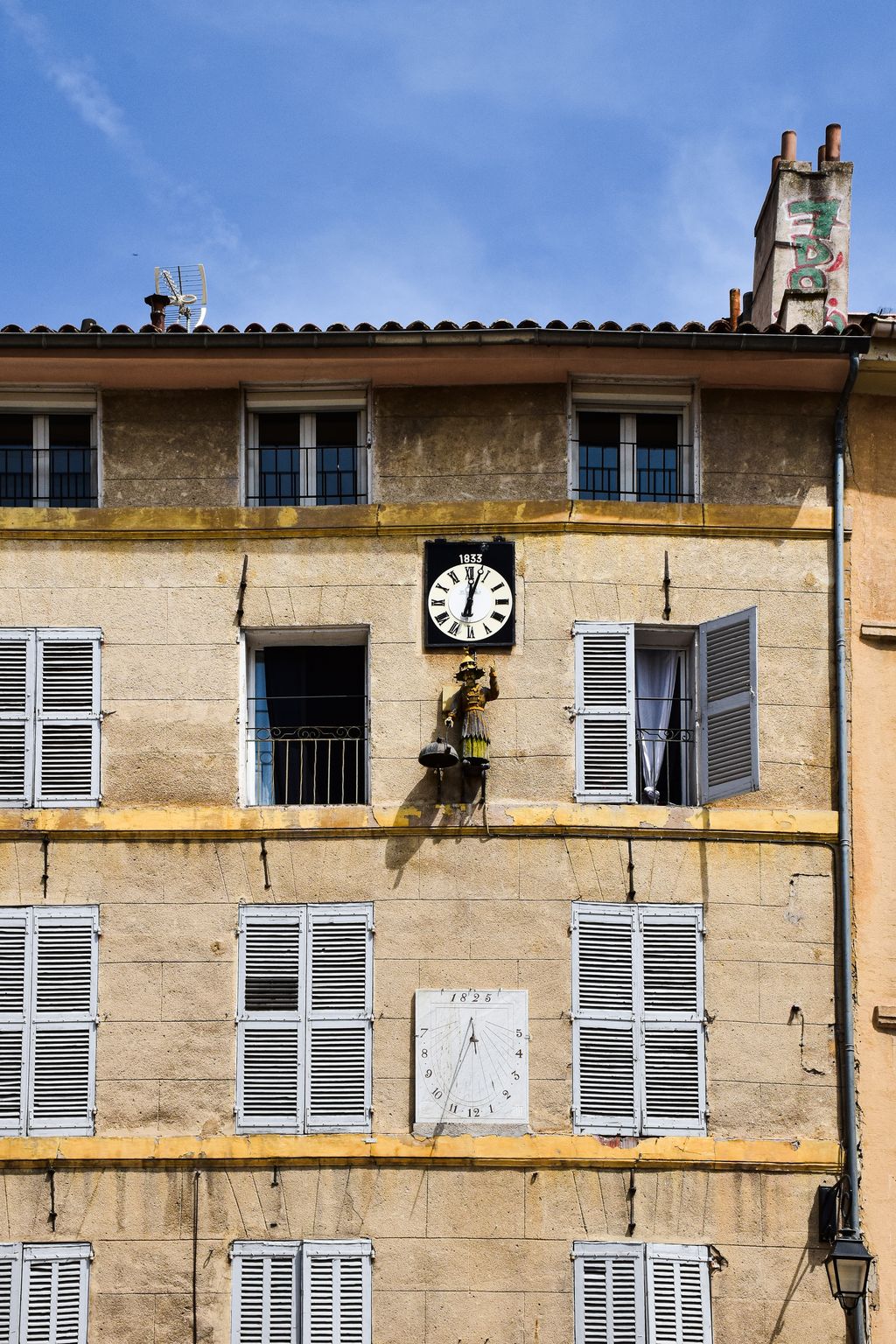 Charming facade with clock and shutters in Aix-en-Provence, France.